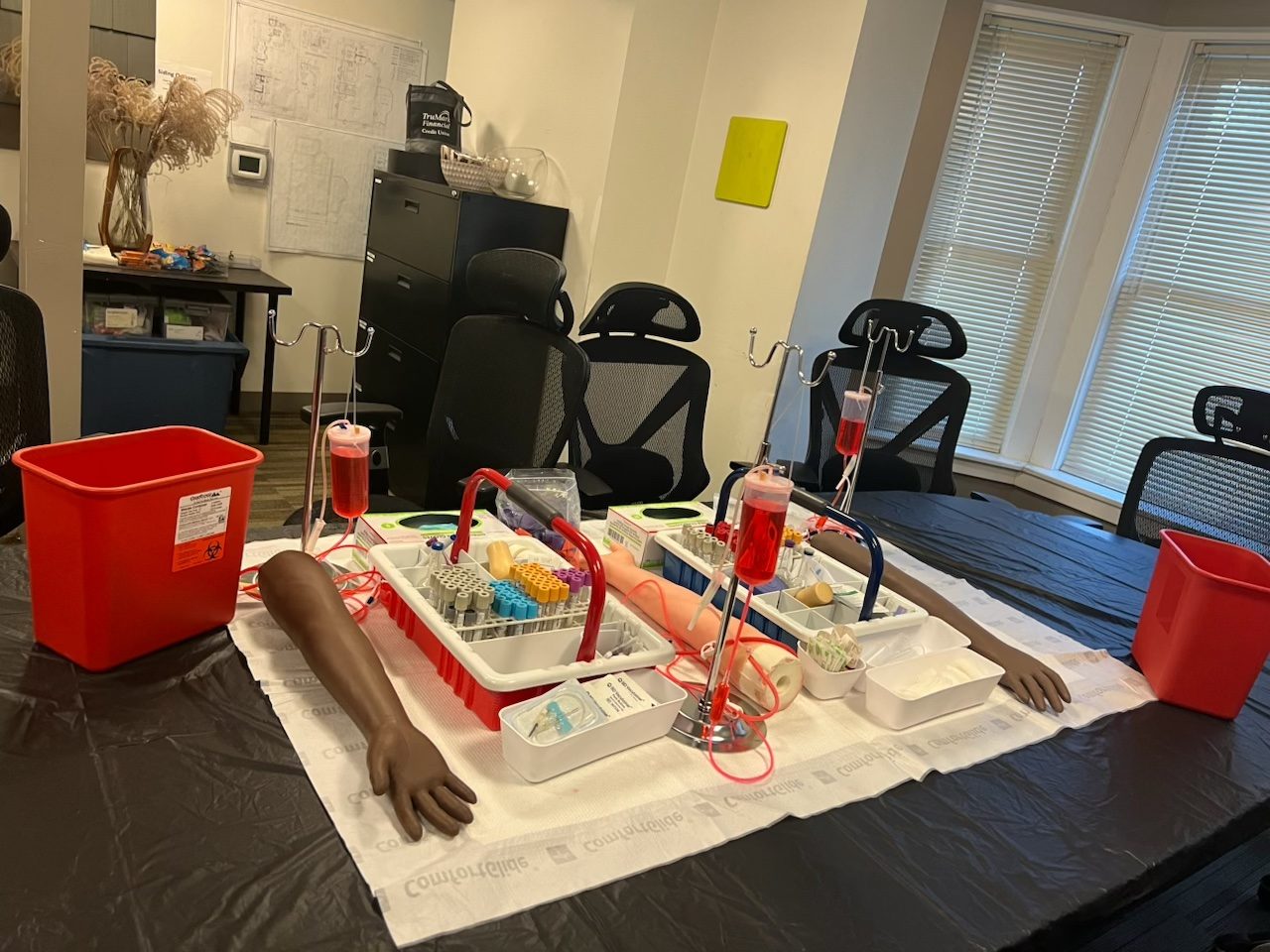 Phlebotomy lab set up with training arms, tube trays, and sharps containers